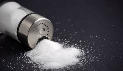 White sea salt for cooking in a small glass bottle. On the salt background, write stop. Concept for...