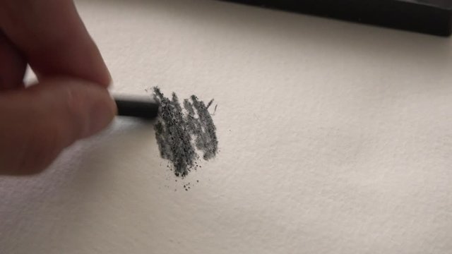 4k Macro shot of sketch artist hand using a charcoal pen to draw. Drawing close up. Abstract drawing on white paper or canvas. Shading style with fingers tip