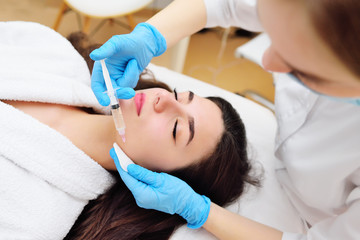 a cosmetic surgeon performs a facial skin rejuvenation procedure using an innovative technology in which plasma enriched with platelets is injected into the patient.
