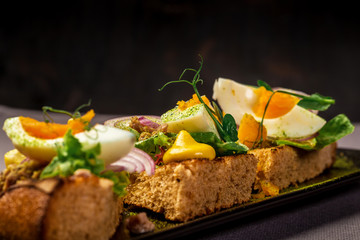 Bruschetta with tuna and herbs on black bread toast with egg