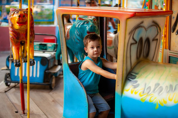 happy little boy on a carousel in a park