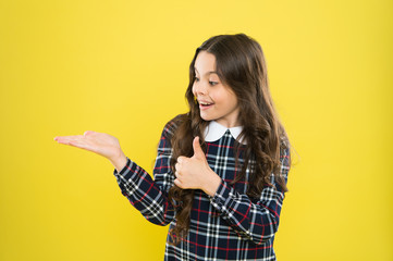 her hair is perfect. presenting product for hair. Small beauty long curly hair. stylish school uniform for kids. beauty of healthy hair. happy childhood. little fashion model yellow wall. copy space.