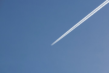 Airplane flies in the blue sky leaving its wake