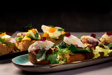 Bruschetta with ricotta cheese, baked beets. snack sandwiches with tuna. Shallow depth of field. Author's menu
