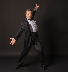 a full-length man on a black background waving his arms in a tuxedo or black 