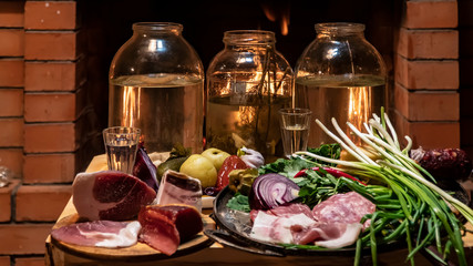 Traditional homemade Russion  herbal infused vodka with cold snacks and firplace on background