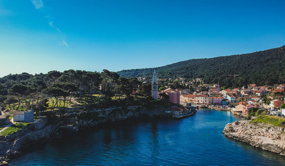 Naklejka na ściany i meble Panoramic aerial photo of the village of Veli Losinj in the Croatian island. View towards the port or marina of the village. Beautiful colorful houses and church are seen.