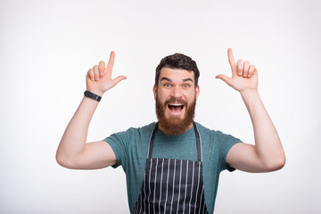 Photo of amazed bearded Chef pointing at copyspace over white background