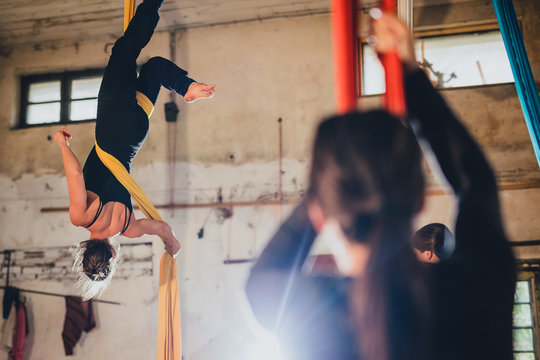 A woman aerial gymnastic dancer on silk rope performing in an industral environment of an abandoned workshop or warehouse.