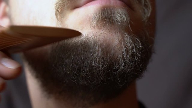 A man combing his beard with comb