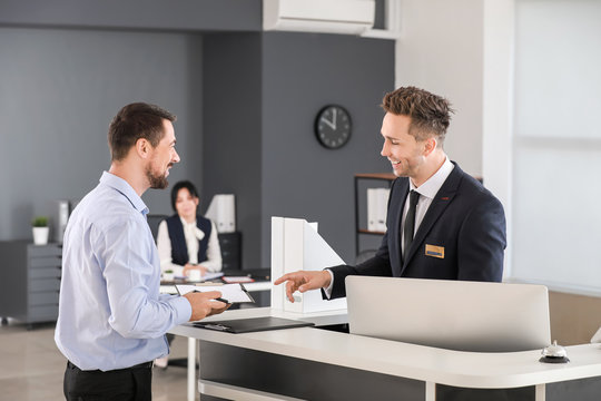 Male receptionist working with visitor in office