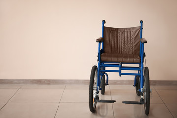 Empty wheelchair near light wall