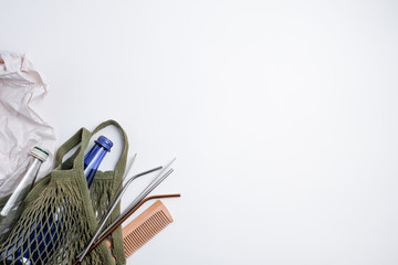 Zero waste stainless steel straw, textile bag, glass bottle and wooden comb on white background