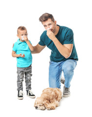Young man and his little son suffering from pet allergy on white background