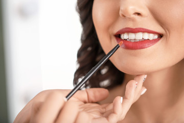 Makeup artist working with beautiful young woman, closeup