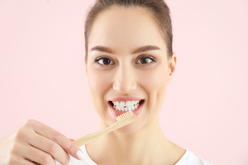 Beautiful young woman with tooth brush on color background