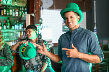 Young man with friends celebrating St. Patrick's Day in pub