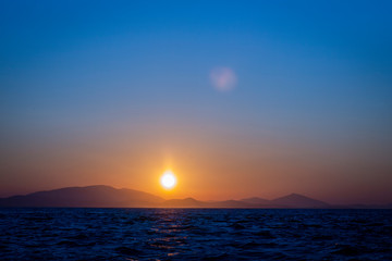 Early morning sunrise over distant mountains and blue sea in Greece