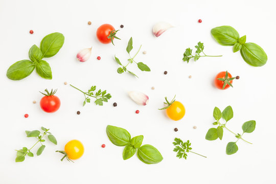 Fresh cherry tomatoes, oregano, basil, parsley, garlic, peppercorns on white background. Top pattern. Top view.