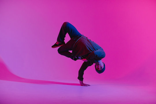 Young Man in a Jumper Dancing Contemporary Dance in Studio. Breakdancing. Dance School Poster. Copy Space. Battle competition announcement. Pink and Blue Background.