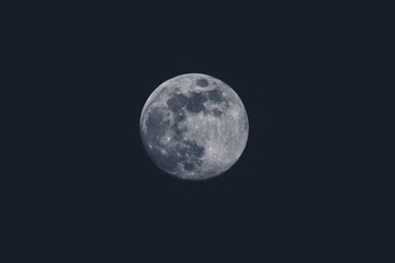 Full moon over dark background sky. Closeup of a moon on the sky, round shape of a moon on black sky.