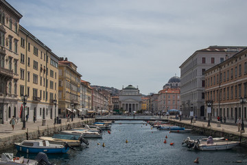 Fototapeta na wymiar Famous ponte rosson in trieste, canal with boats, looking towards the red bridge and church of Antonio Taumaturgo on a sunny day.