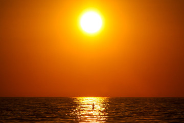 Fototapeta na wymiar Sunny evening on a beach in Puerto Escondido, Mexico, with a man on a SUP board paddling under the sun. Concept of an enjoyment under the sun.