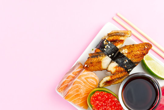 traditional japanese sushi set on a white plate isolated on a pink background. tasty set of sushi, nigiri, sahimi and maki. delicious dinner or lunch for one person. flat lay