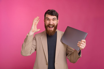 Amazed young man in suit received his new laptop