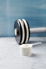 Scoop of Whey Protein and a dumbbell. Bodybuilding food supplements on stone / wooden background. Close up. Copy space.