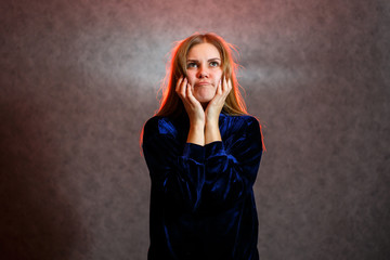 Girl with blond hair emotionally posing on a gray background. Her hair is lit in red