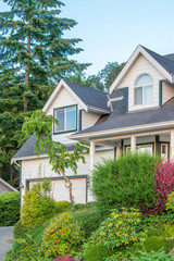 A perfect neighborhood. Houses in suburb at Summer in the north America. Fragment of a luxury house with nice window over blue and white sky.