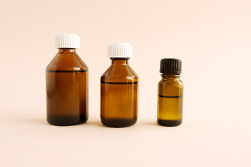 Glass jars, bottles with essential herbal aromatherapy oils for spa treatments on a pink background.