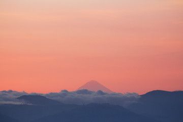 Silhouettes of mountains with clouds and volcano in the background - A view of the volcanoes of Guatemala - Sunset between mountains