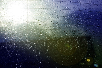 Fototapeta Krople deszczu na tylnej szybie samochodu z chmurami w tle. obraz