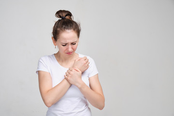Obraz premium Girl in a white T-shirt massages a brush. Concept of joint pain. close up.