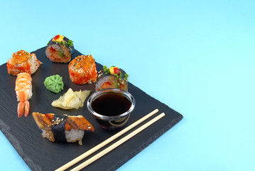 traditional japanese sushi set serviced on black stone. tasty set of sushi, nigiri, sahimi and maki. delicious dinner or lunch for one person. isolated on blue