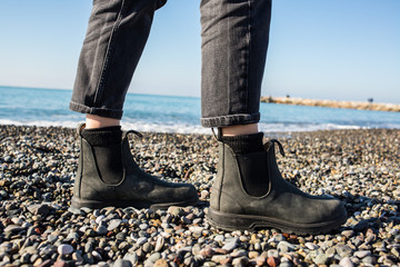 Chelsea boots classic black leather rubber sole. Focus on legs of hipster woman wearing denim black...