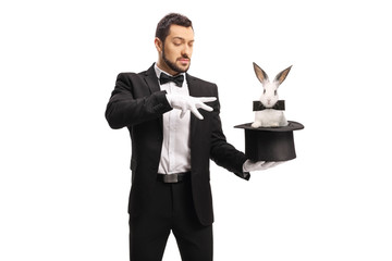 Young male magician making a magic trick with a rabbit in a top hat