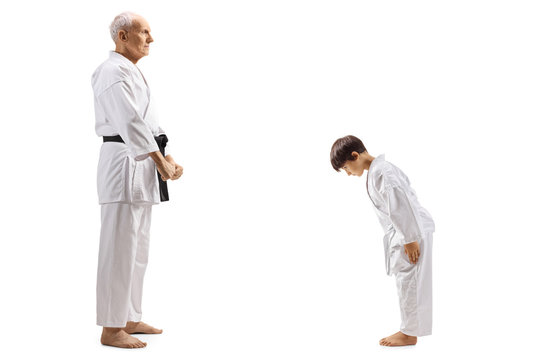 Boy in karate kimono bowing in front of his elderly karate instructor