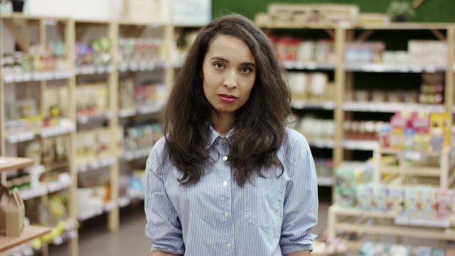 Young pretty woman shrugging shoulders and rising her hands up , making a helpless gesture with hands, looking upset and confused.