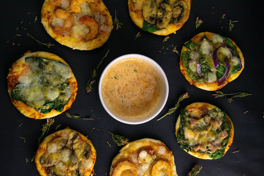 Small mini pizza. Set of different mini pizzas. Pizza: with shrimp, with mushrooms, with spinach and onions, with bacon, with paperoni, with tomatoes