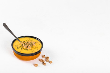 Pumpkin soup-puree with cream, wheat croutons and greens on a light background