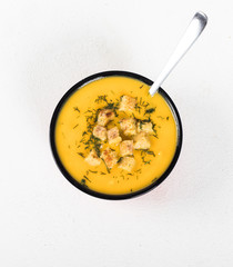 Pumpkin soup-puree with cream, wheat croutons and greens on a light background