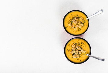 Pumpkin soup-puree with cream, wheat croutons and greens on a light background