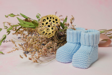 Little knitted socks for infant baby and bouquet of flowers. Baby booties footwear. Baby birth concept.