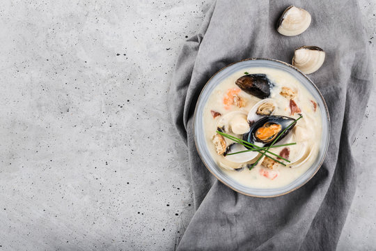 Clam chowder in a gray plate. The main ingredients are shellfish, broth, butter, potatoes and onions.