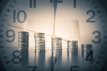 Stacks of coins on clock background. Saving money and growing wealth concept. 