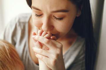 Beautiful woman with child. Woman in a gray t-shirt. Family sitting on a windowsill.
