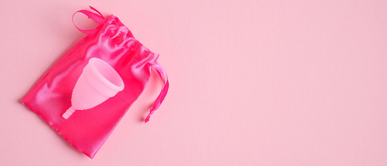 Silicone menstrual cup and bag on pink background. Alternative menstrual hygiene product. Critical days, menstruation cycle, female healthcare concept